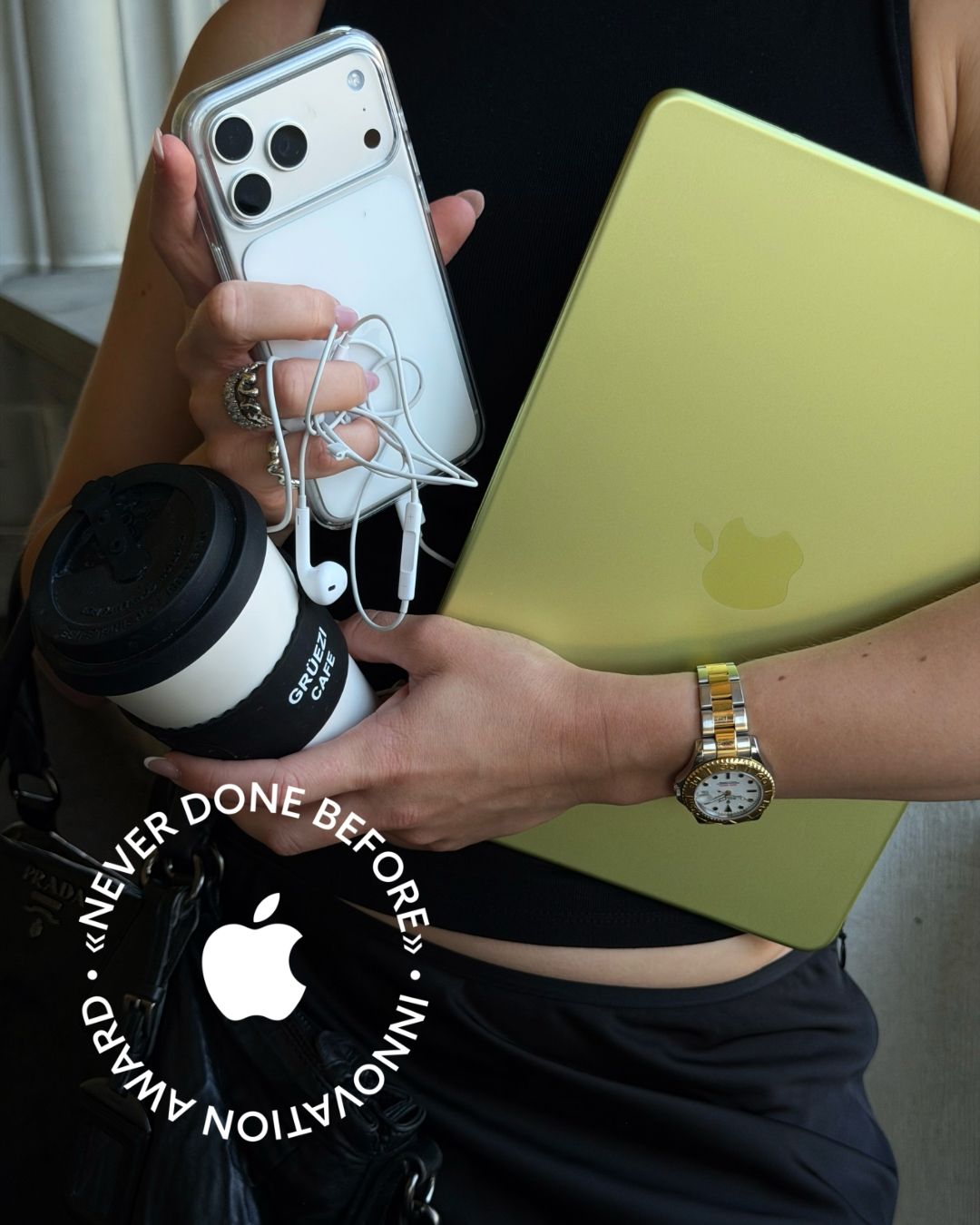 Das Never-Done-Before-Award-Badge: MacBook Neo, iPhone und Grüezi-Becher in der Hand