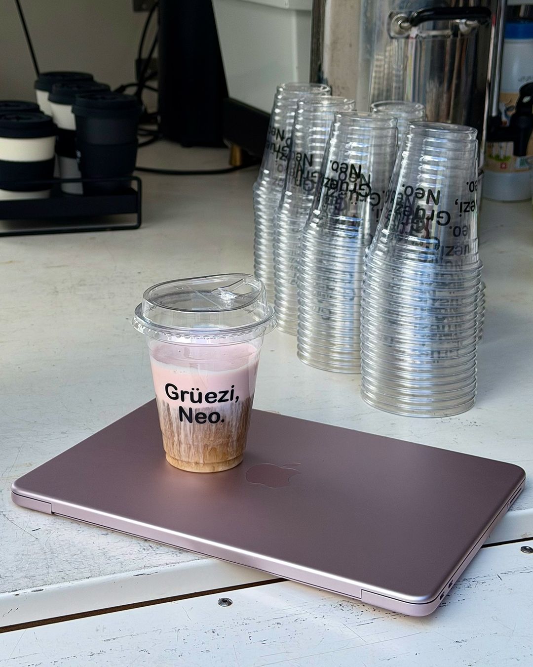 Grüezi Neo Eiskaffee auf einem MacBook Neo an der Kaffeebar