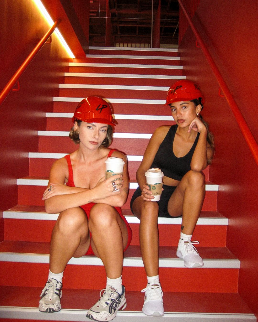 Zwei Frauen mit roten Lucky-Punch-Bauhelmen auf der roten Treppe des neuen Studios